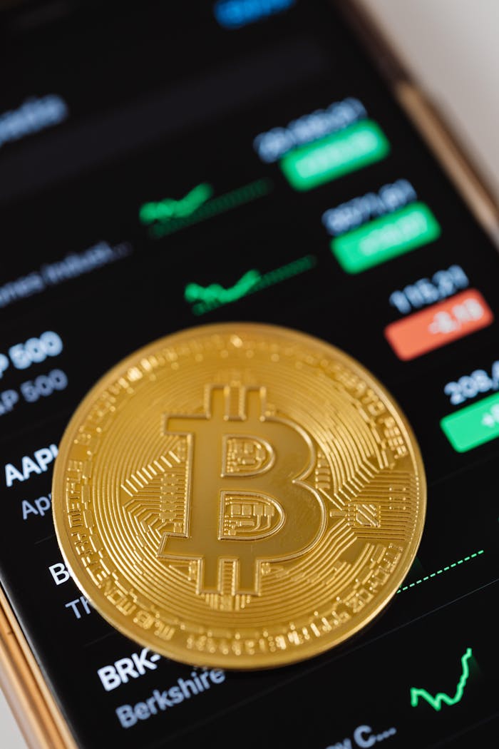 The Art of Drawing Readers In: Your attractive post title goes here Close-up of a golden Bitcoin coin on a smartphone displaying stock trading data, symbolizing modern digital finance.