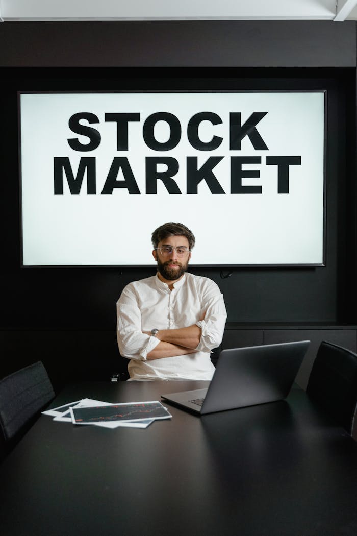 Crafting Captivating Headlines: Your awesome post title goes here Professional businessman with arms crossed in front of a stock market display in a modern office setting.